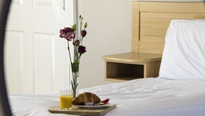 A hotel room with a bed, a bedside table with a tray of breakfast, and a vase with flowers. - The Harbour Inn (Buncrana)