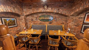 A brick-walled restaurant with wooden tables and chairs, a clock, and framed pictures on the walls. - The Harbour Inn (Buncrana)