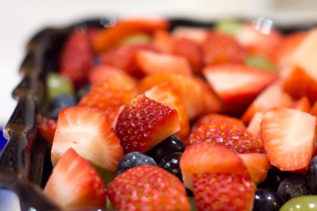 Primer plano de una ensalada de frutas con fresas, arándanos y trozos de melón.