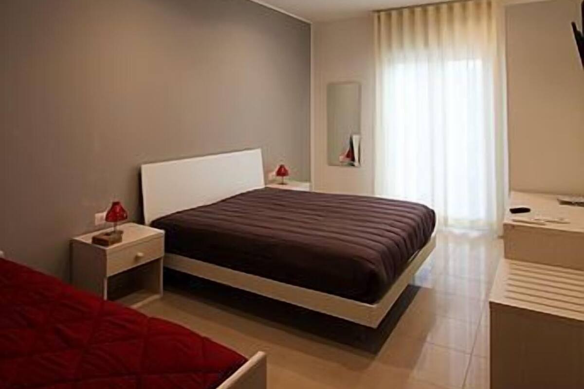 Un dormitorio moderno con una cama grande, mesitas de noche, un espejo y un escritorio.