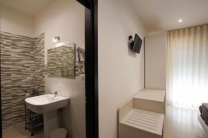 Un baño moderno con una pared de diseño de piedra, un lavamanos y un espejo.