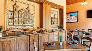 Un restaurant avec des meubles en bois, un buffet proposant divers plats et des œuvres d’art accrochées aux murs.