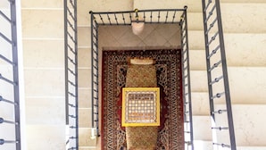 Un escalier en colimaçon, agrémenté d’une moquette à motifs et d’un luminaire suspendu.