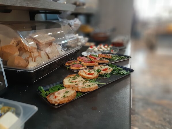 A buffet with various food items including bread, sandwiches, and salads.