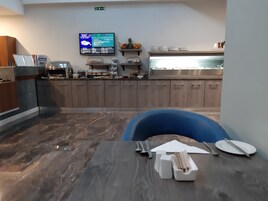 A modern kitchen with wooden cabinets, a stainless steel sink, and a digital menu display.
