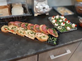 Une table de buffet proposant divers aliments, notamment du pain garni, un plateau de hors-d'œuvre et un récipient contenant du pain.
