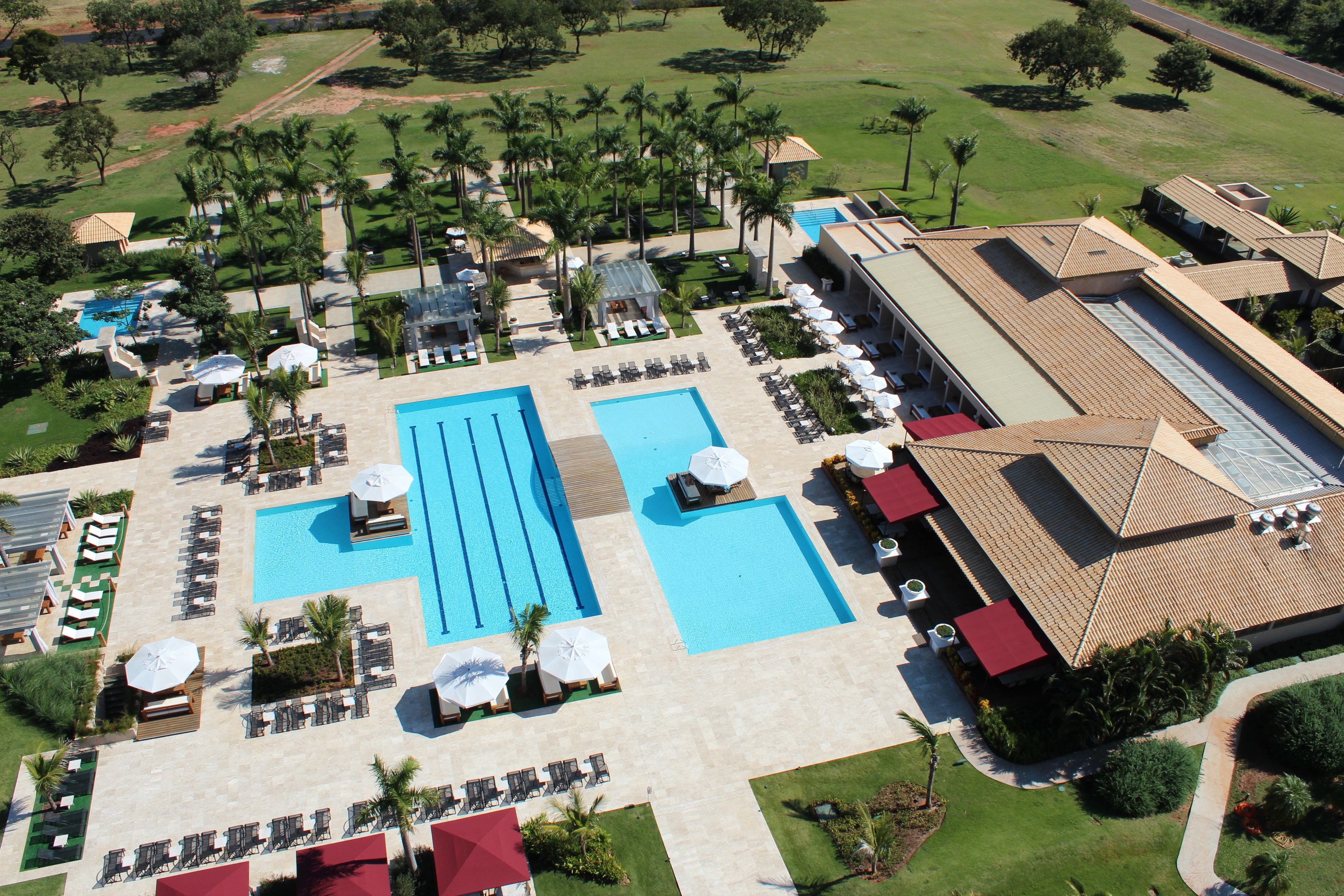 An aerial view of a resort with multiple swimming pools, sun loungers, and palm trees.
