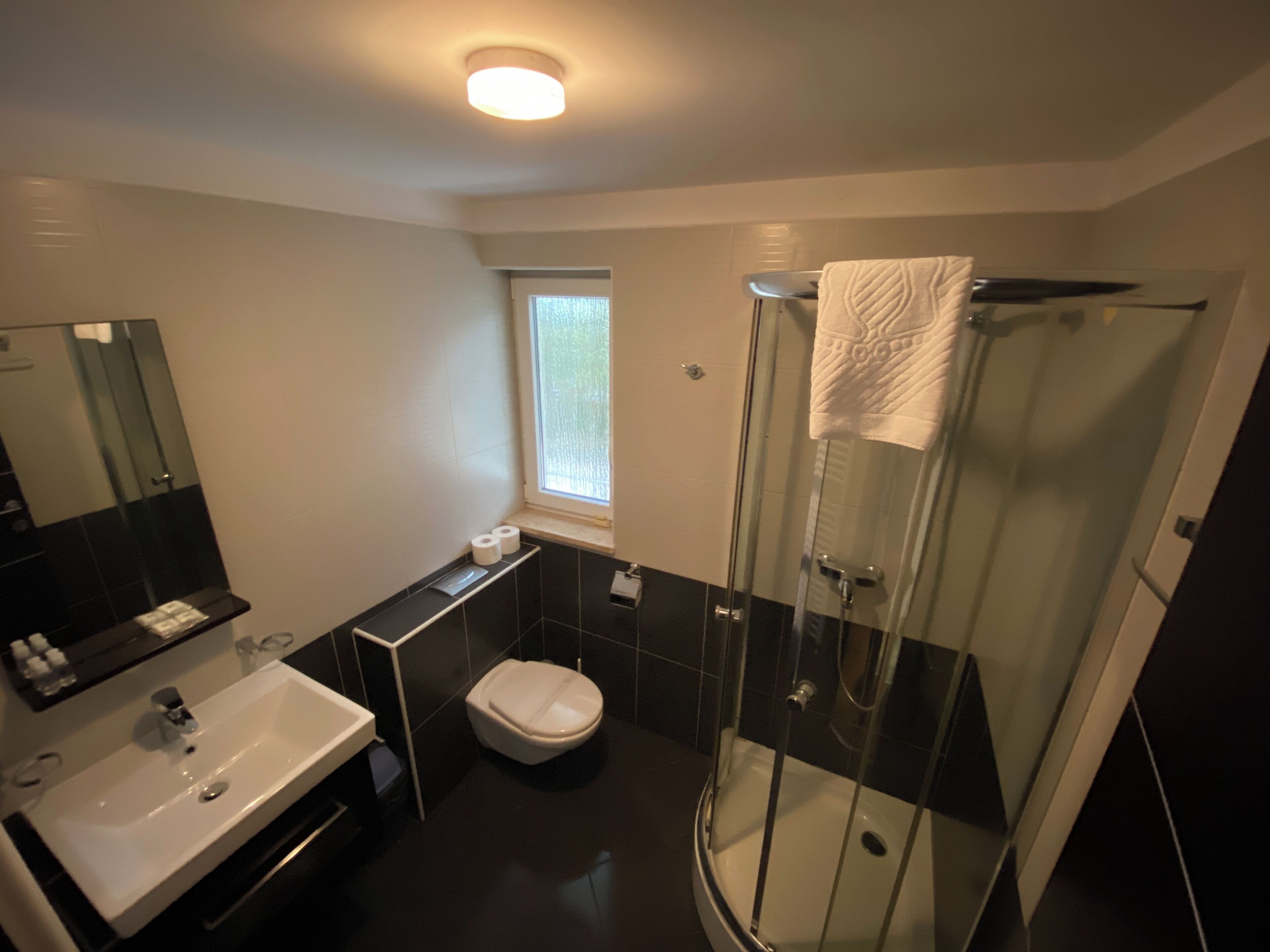 Een moderne badkamer met een douchecabine van glas, een wit wastafelmeubel en een toilet.