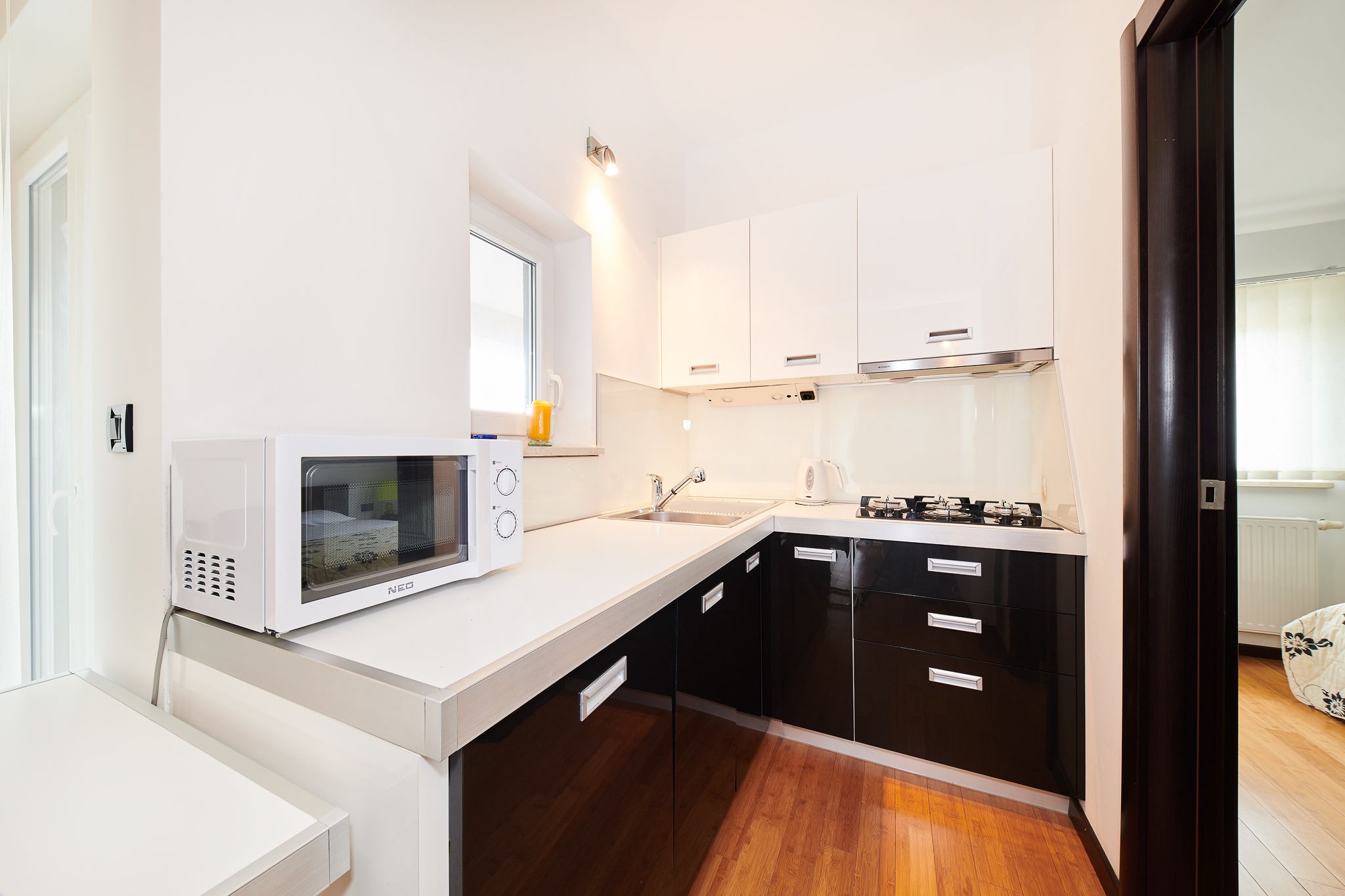 A modern kitchen with white cabinets, a microwave, a sink, and a stove.
