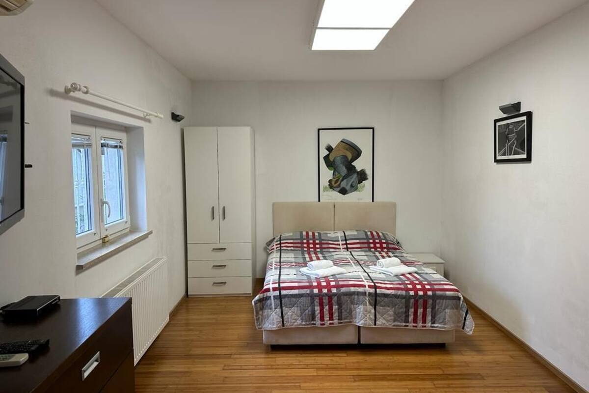 A bedroom with a bed, a wardrobe, a desk, and a window.