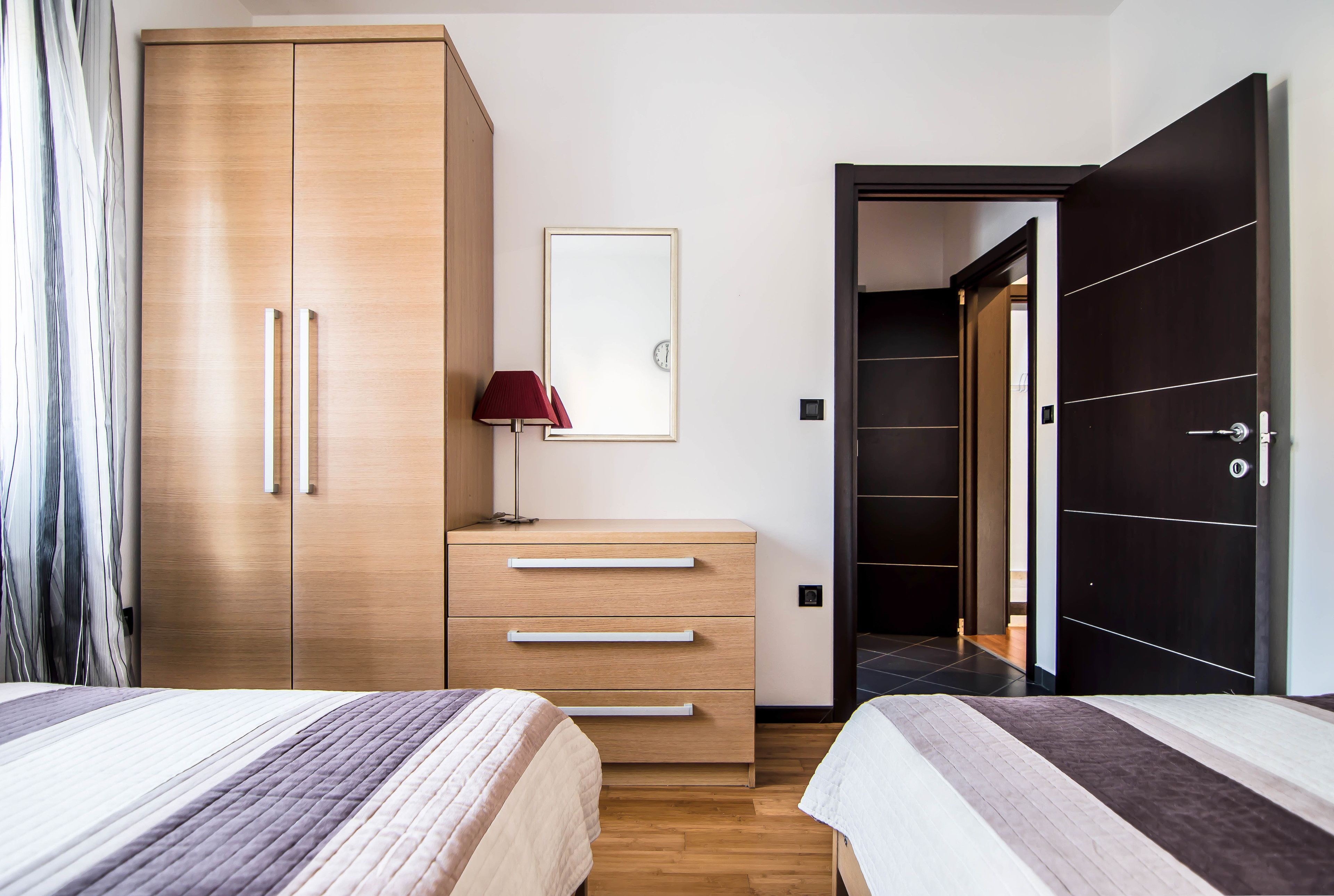 Una camera da letto con due letti, un armadio in legno, un comodino con una lampada e un quadro appeso al muro.
