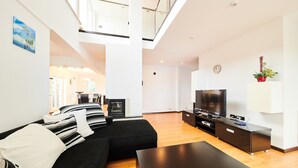 Un salon moderne avec un canapé noir, un téléviseur à écran plat et un plancher en bois.