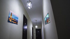 A hallway with two doors, a chandelier, and two framed pictures on the walls. - Il Centro Short Lets (Valguarnera Caropepe)