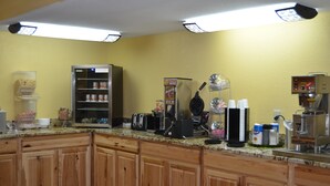 Una cocina con armarios de madera, microondas, cafetera y varios electrodomésticos.