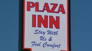 Señal de Plaza Inn con el texto 'Quédese con nosotros y sienta comodidad'.