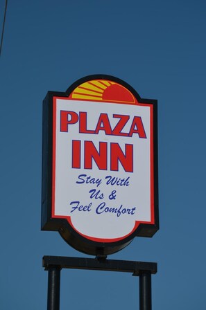 Señal de Plaza Inn con el texto 'Quédese con nosotros y sienta comodidad'.