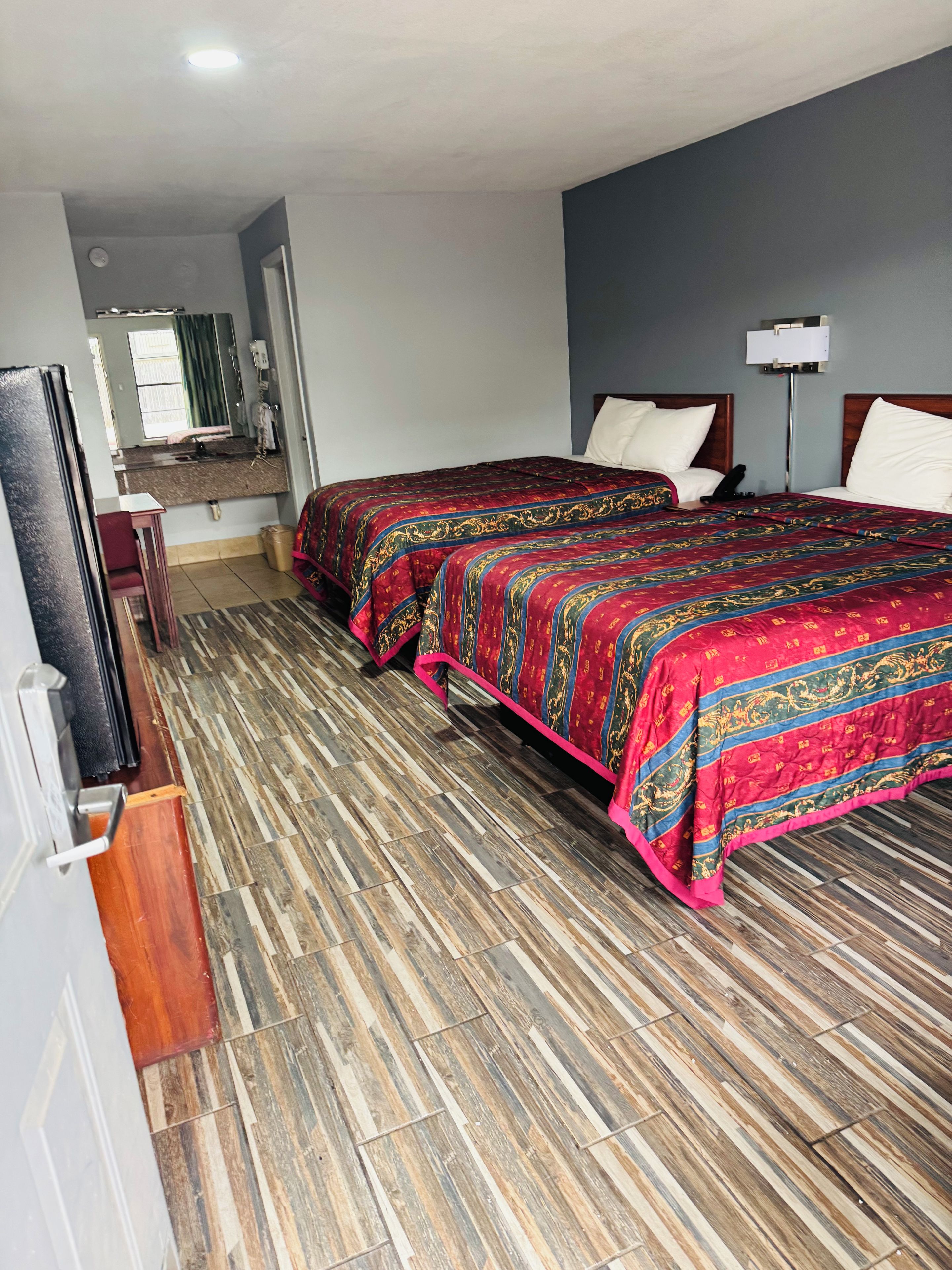 A hotel room with two beds, a bathroom, and a small sitting area.