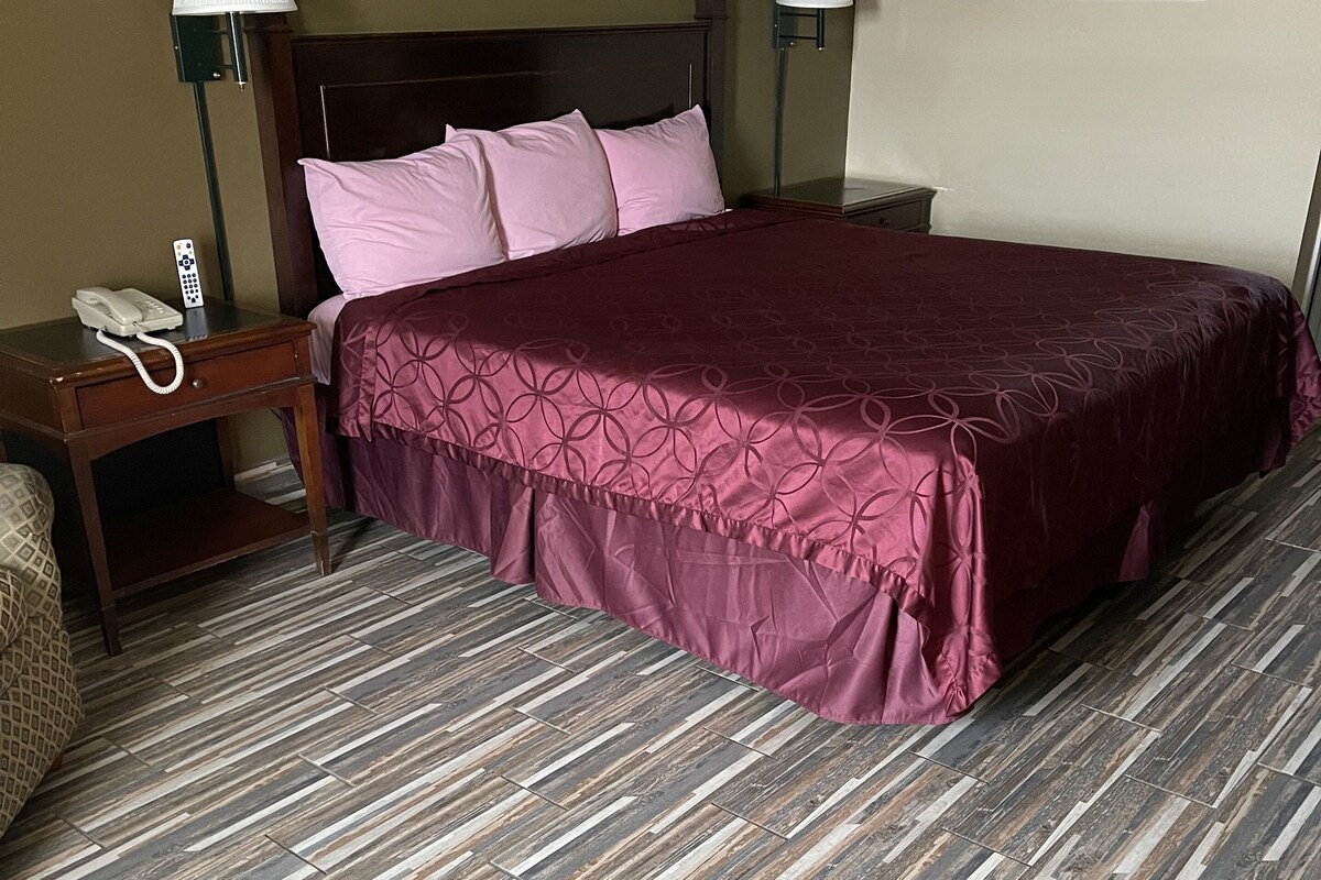 Una habitación de hotel con una cama de madera, un teléfono en la mesita de noche y dos lámparas de pared.
