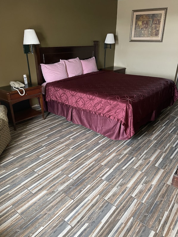 A hotel room with a wooden bed, a telephone on the nightstand, and two wall lamps. - Plaza Inn Big Spring (Big Spring)