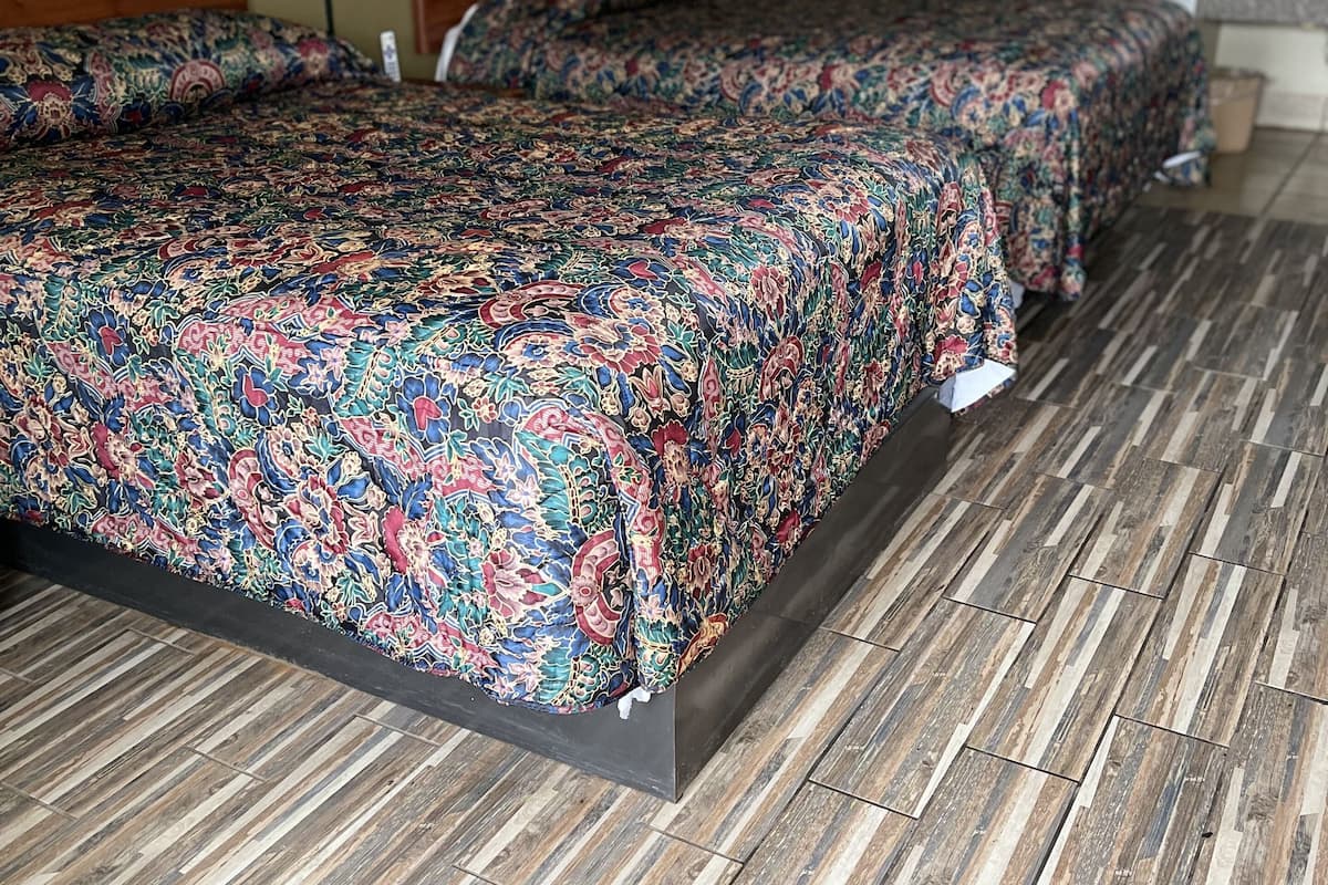 Quarto de hotel com uma cama grande, uma mesa de cabeceira, um abajur e um quadro na parede.