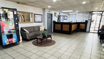 Un vestíbulo con mostrador de recepción, un sofá, una mesa de centro y una máquina expendedora.