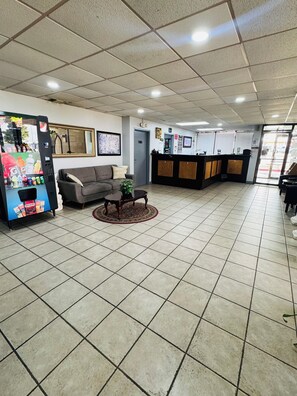 A lobby with a reception desk, a sofa, a coffee table, and a vending machine. - Plaza Inn Big Spring (Big Spring)