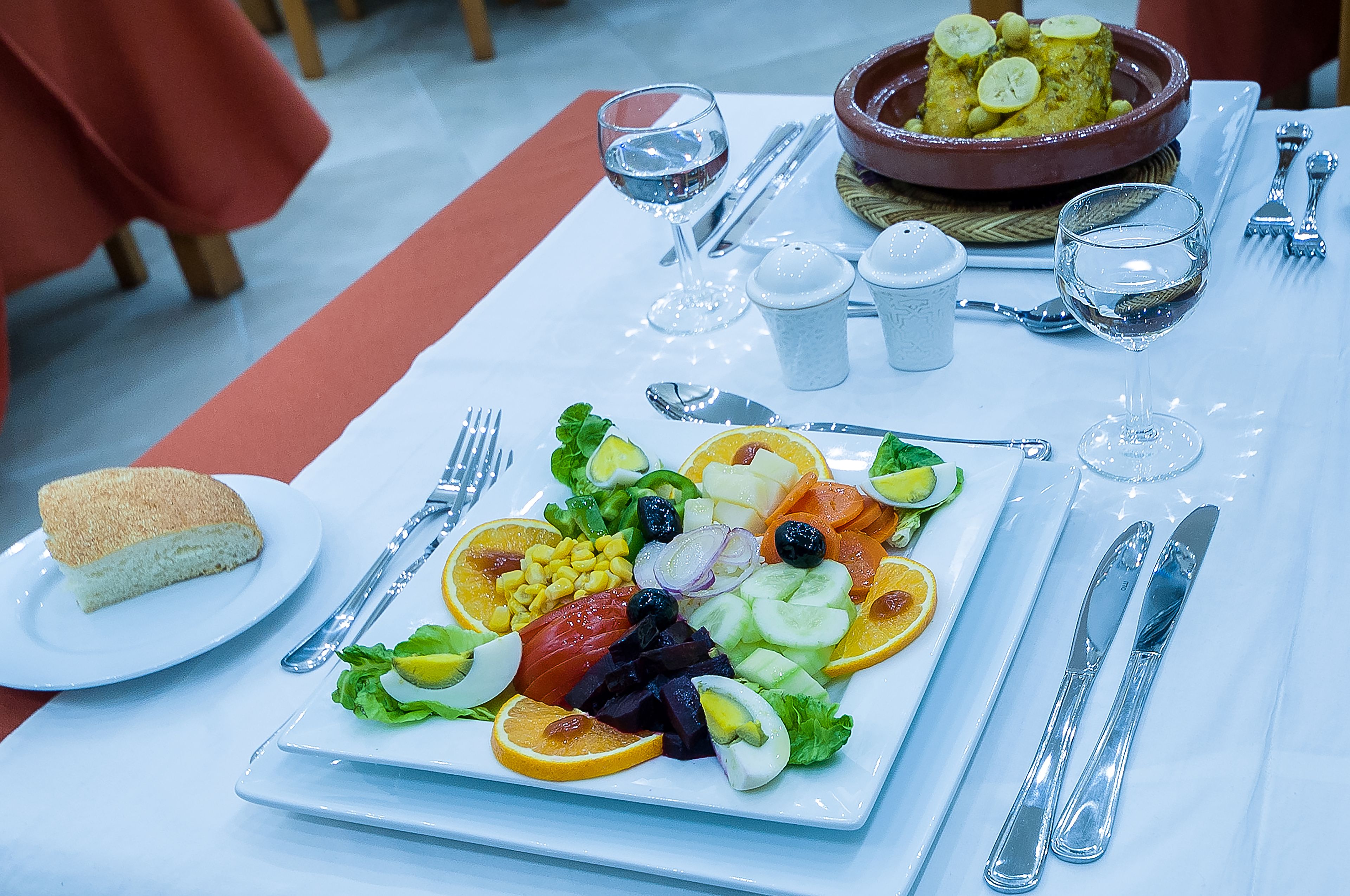 A table set with a salad, bread, and a bowl of food.