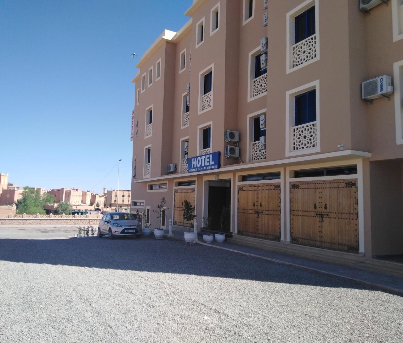 Un hotel con letrero, varios balcones y una entrada con portón.