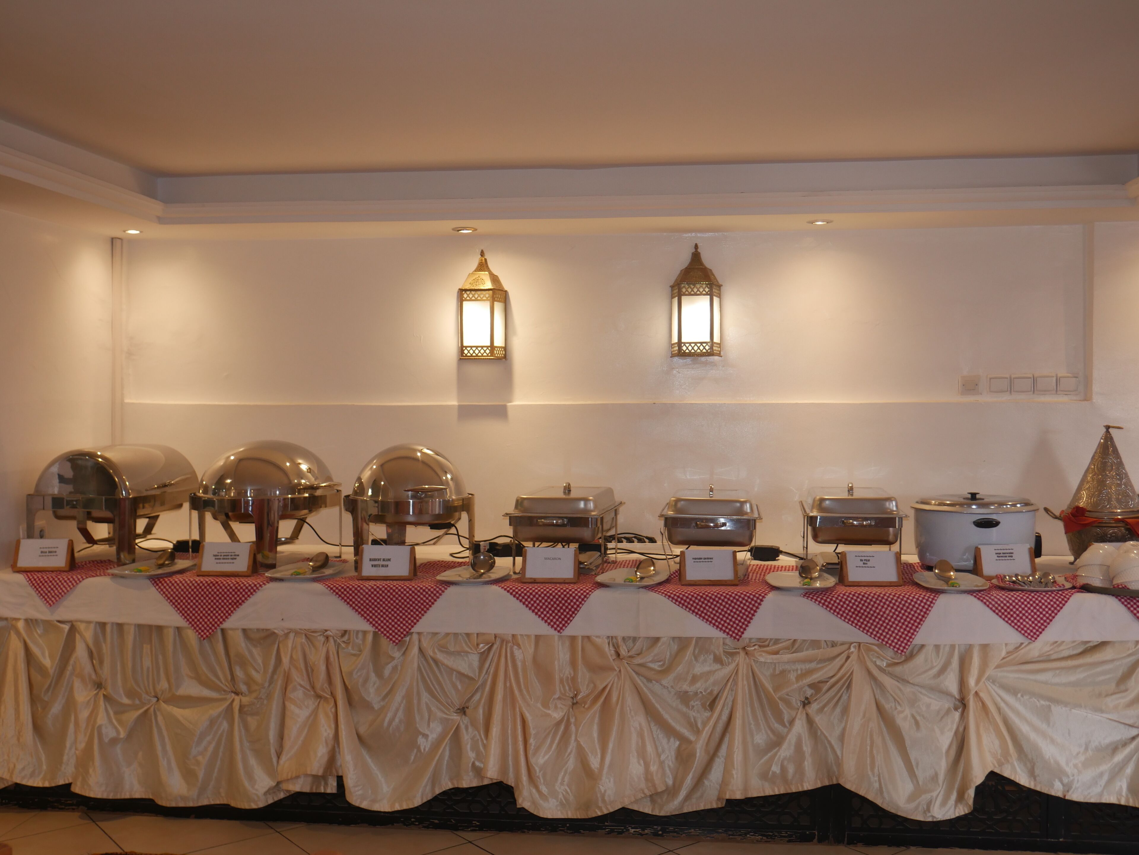 A buffet setup with various food stations, including a hot pot and a rice cooker, under warm lighting.
