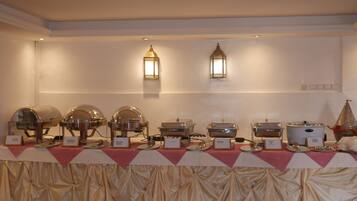 A buffet setup with various food stations, including a hot pot and a rice cooker, under warm lighting.