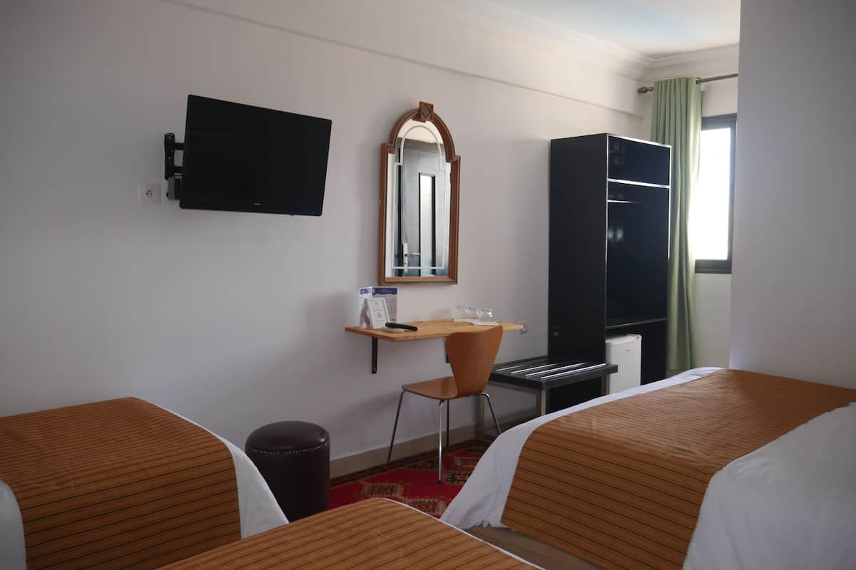 A hotel room with two beds, a desk, a chair, a television, and a wardrobe.