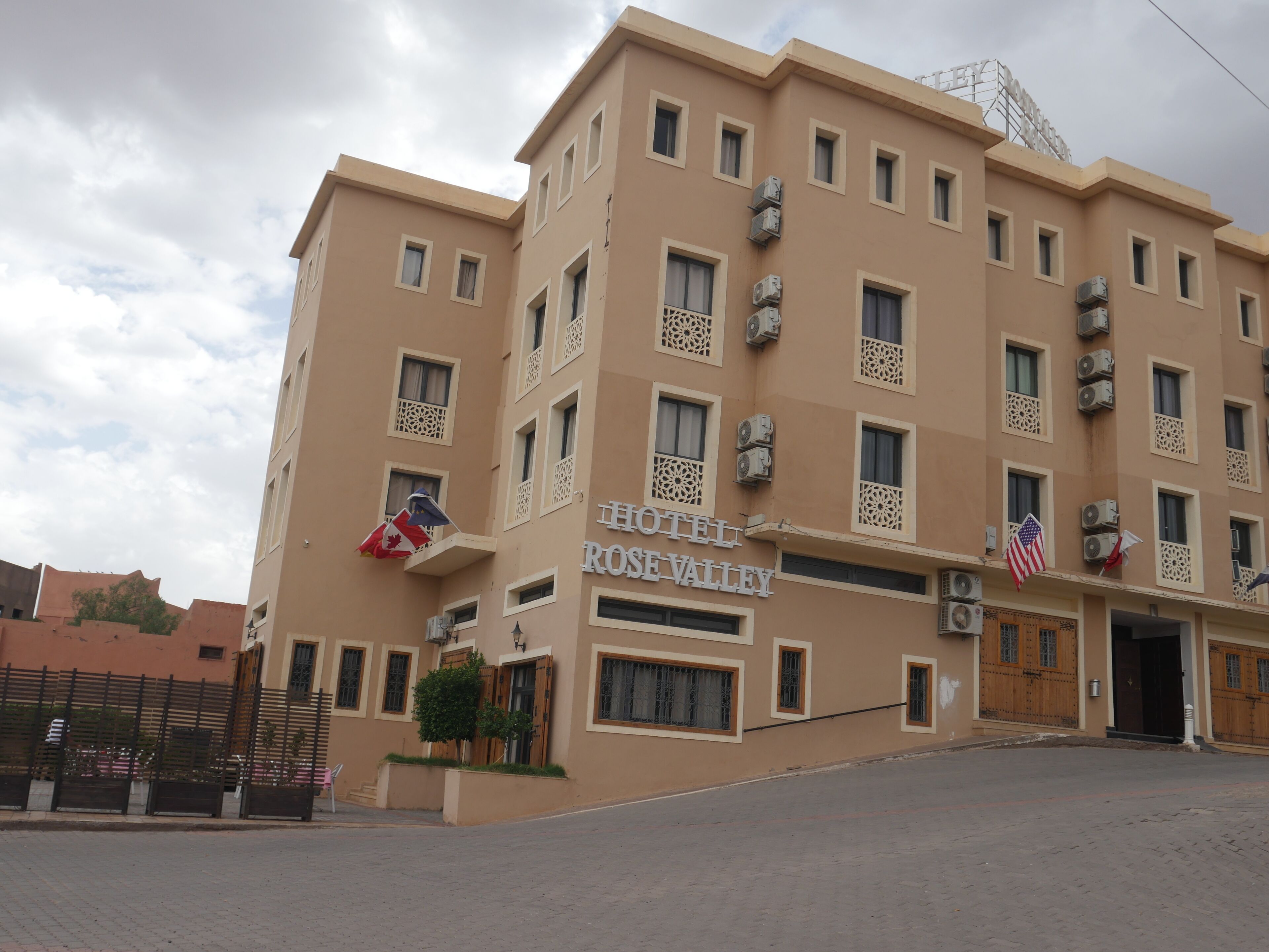 A multi-story hotel with a beige facade, multiple air conditioning units, and a sign reading "HOTEL ROSE VALLEY".