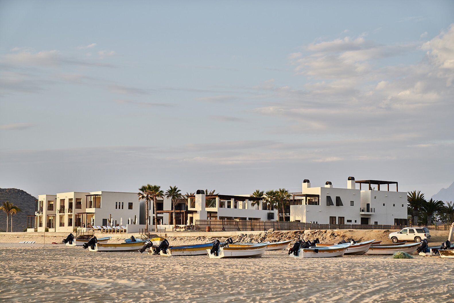 A beachfront property with modern architecture, a sandy beach, and several boats.