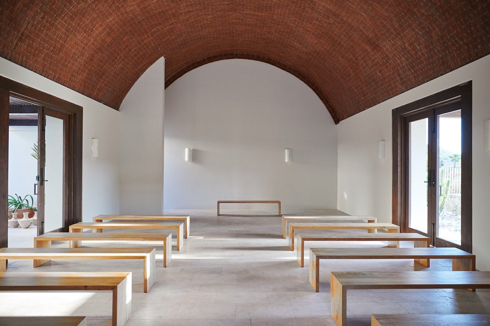 An interior with a high arched ceiling, rows of wooden benches, and large windows allowing natural light.