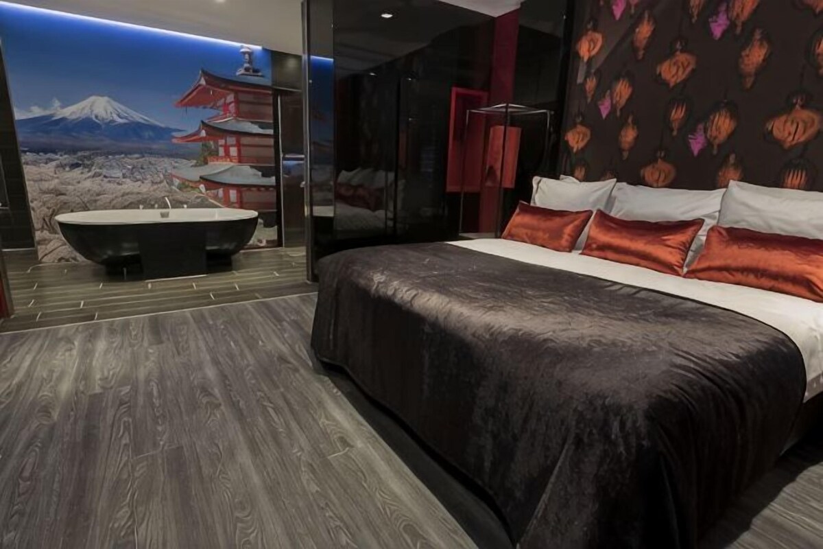Un dormitorio moderno con una cama grande, una bañera y un mural escénico en la pared.