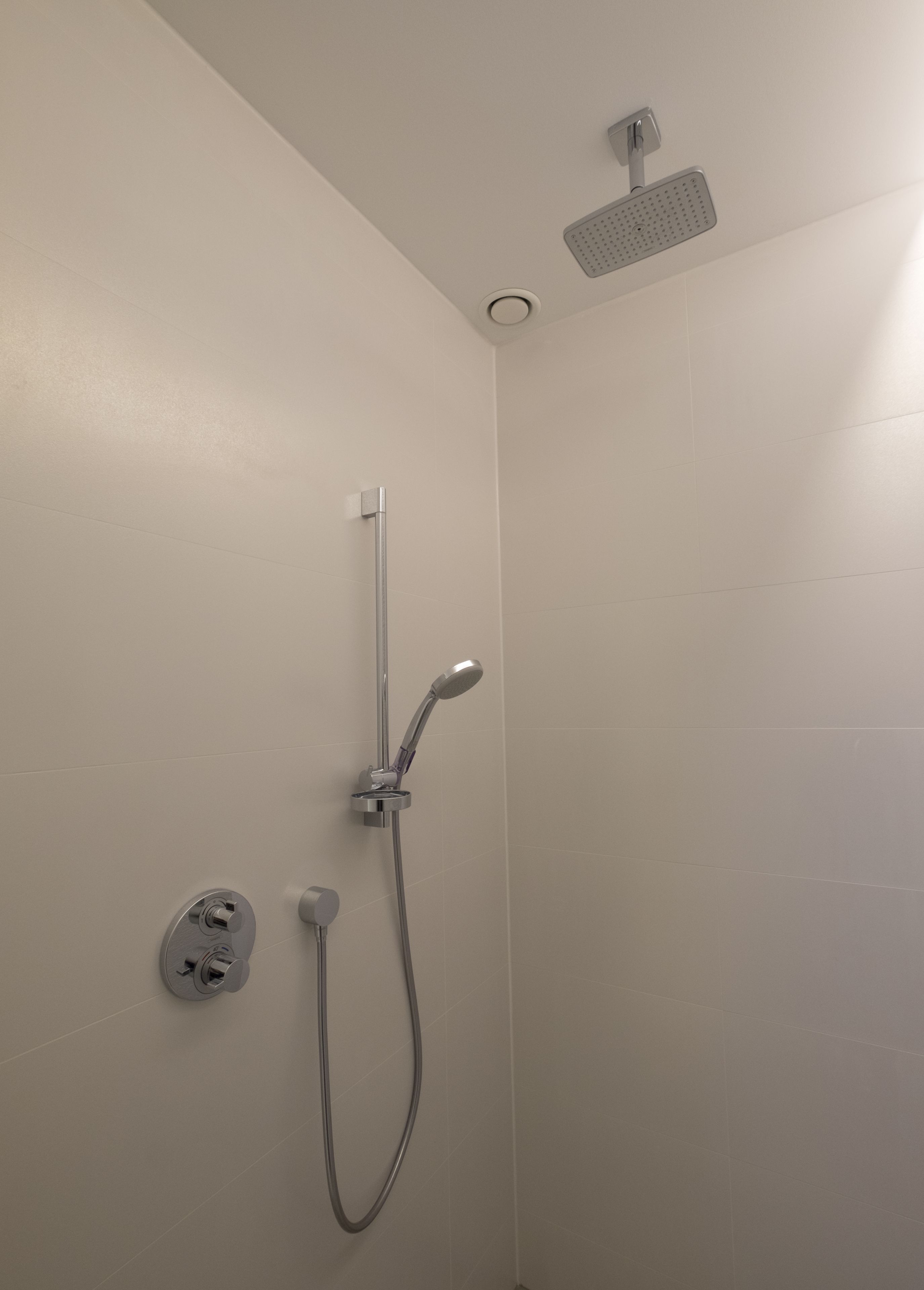 Een douche met een handdouche en een bedieningspaneel aan de muur.