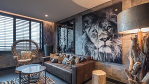 Una sala de estar moderna con un gran felpudo de estampado de leopardo, un sofá de cuero con cojines estampados, una mesa redonda y una obra de arte de gran tamaño con estampado de leopardo.