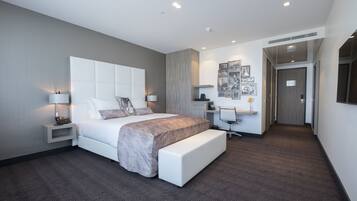 A modern hotel room with a large bed, bedside tables, a desk, and a seating area.