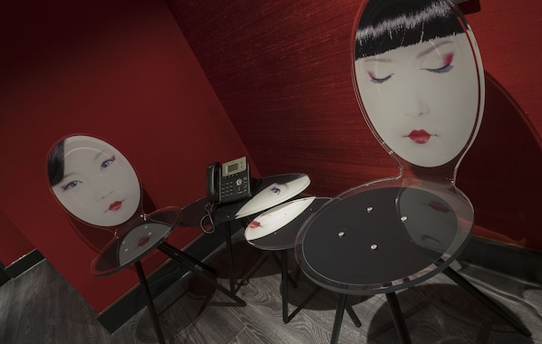 A room with a red wall, a mirror, and two round tables. - Van der Valk Hotel Utrecht (Utrecht)