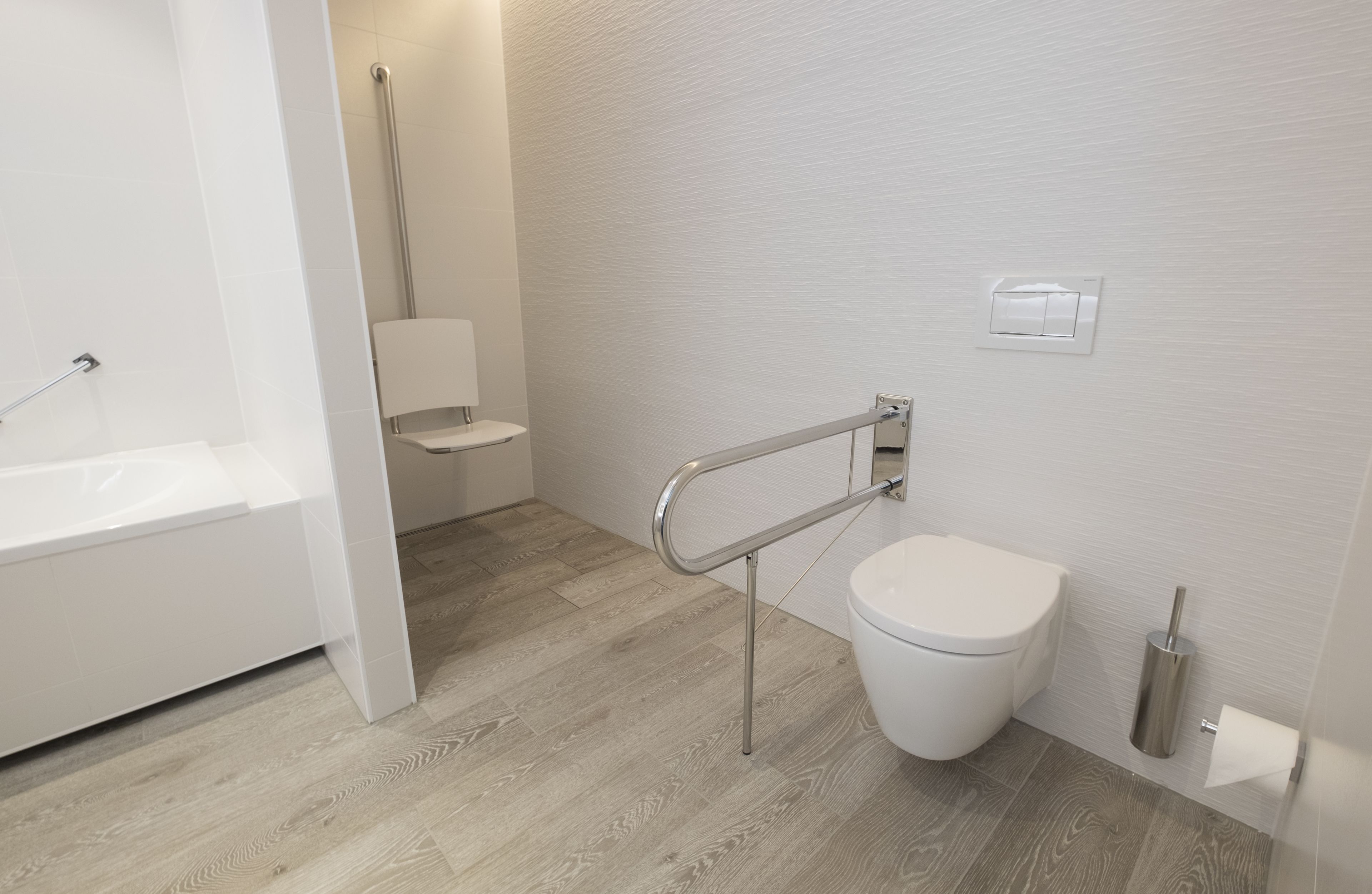 Ein modernes Badezimmer mit Toilette, Duschbereich und Haltestange in der Nähe der Toilette.