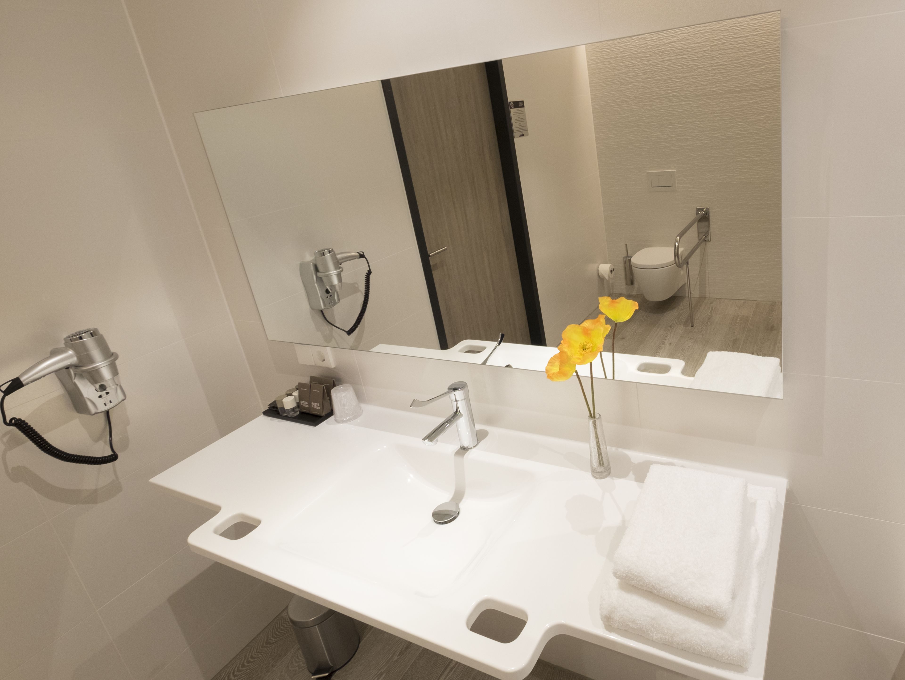Une salle de bain moderne avec un lavabo blanc, un miroir et un sèche-cheveux.