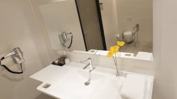 Un baño moderno con un lavabo blanco, un espejo y un secador de pelo.