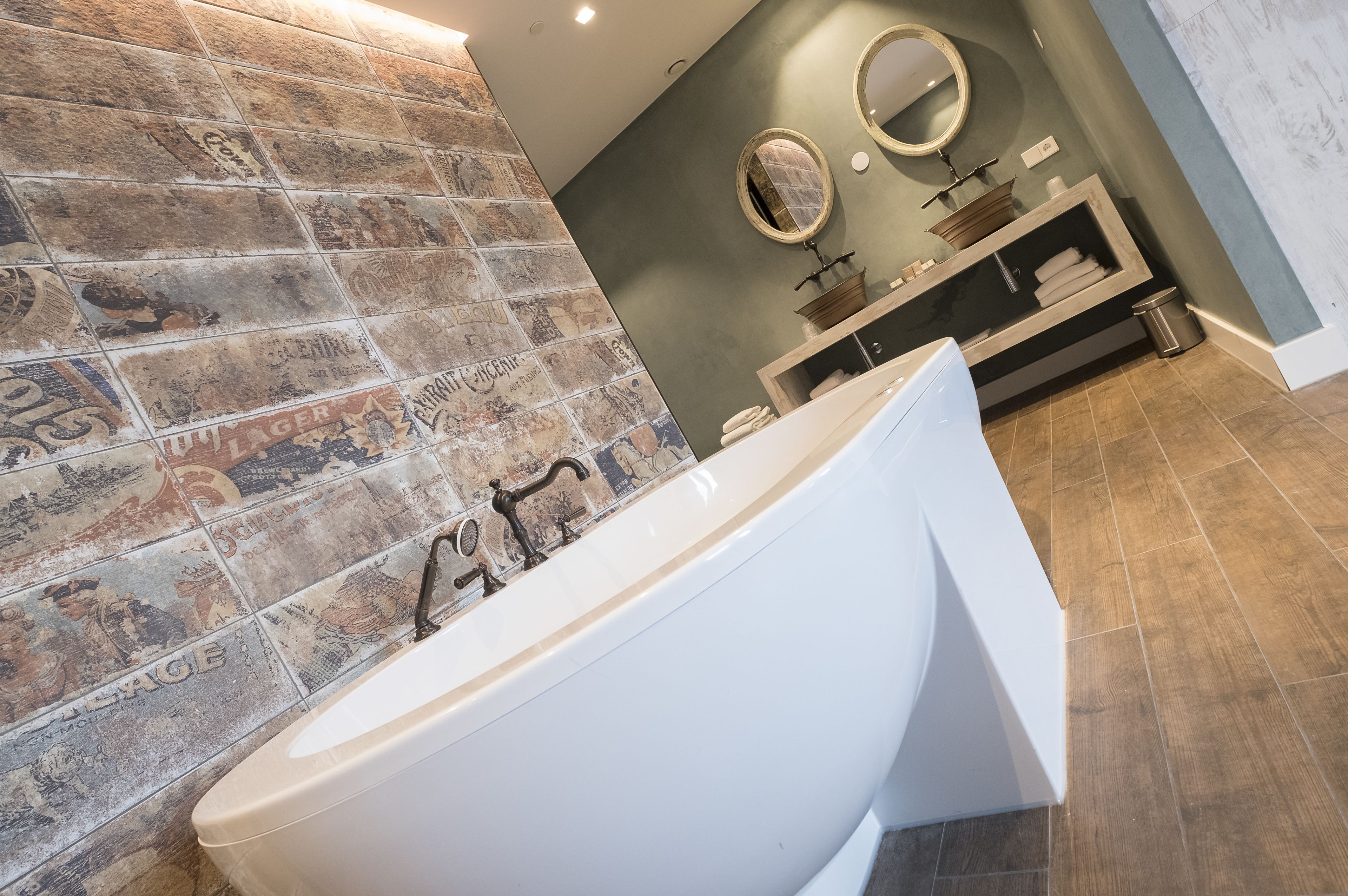 Une salle de bain moderne avec une baignoire sur pieds, un meuble-lavabo avec un miroir et un mur recouvert de carreaux au style rétro.