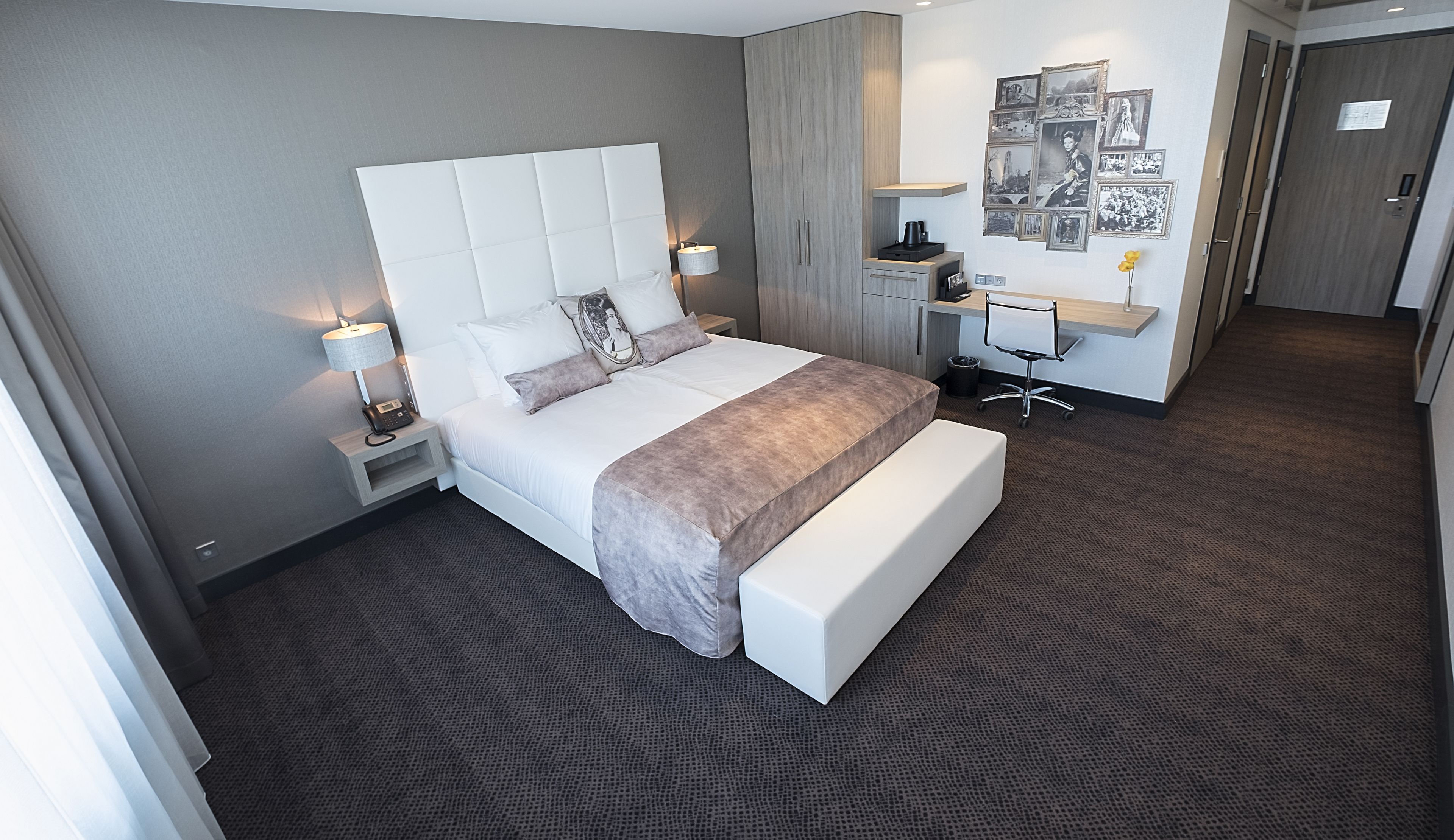 Una habitación de hotel moderna con una cama grande, mesitas de noche, un escritorio y un armario.
