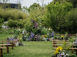 A garden wedding venue with wooden benches and a variety of flowers.