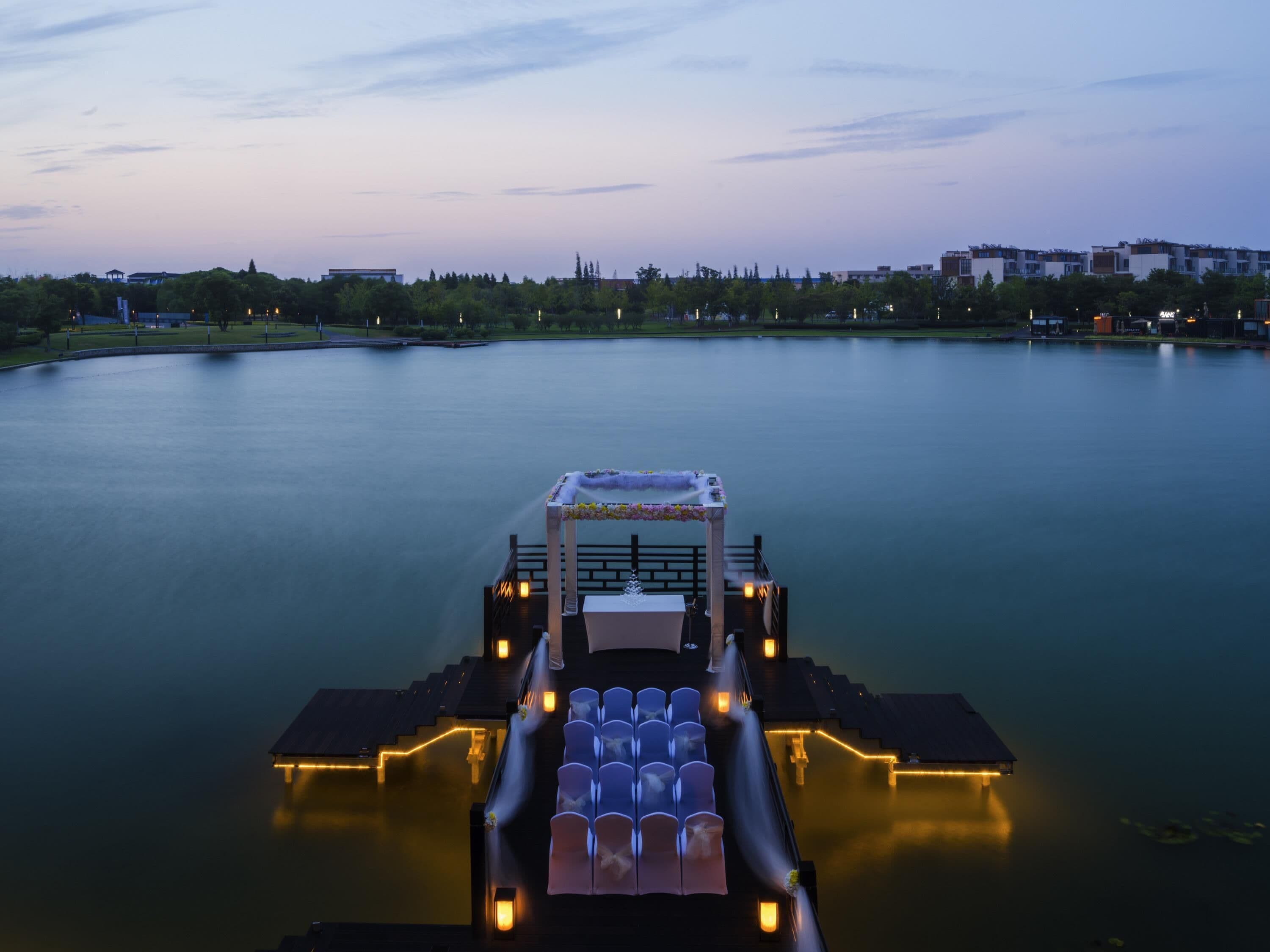 A boat docked at a calm lake with a cityscape in the background.