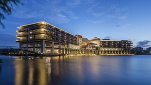 Un hotel de varios pisos con balcones, vistas al agua y un diseño arquitectónico moderno.
