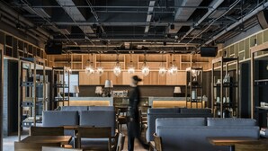 Un interior de restaurante moderno con mobiliario de madera, iluminación colgante y techos a la vista.