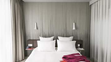 A modern hotel room with a large bed, two bedside tables, and a headboard with vertical lines.