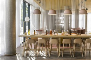 Un comedor moderno con una mesa larga dispuesta para seis personas, rodeada por seis taburetes.